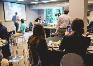 Businessmen, businesswoman and workers from back seated, recording and listen a seminar with breakfast in a hotel salon